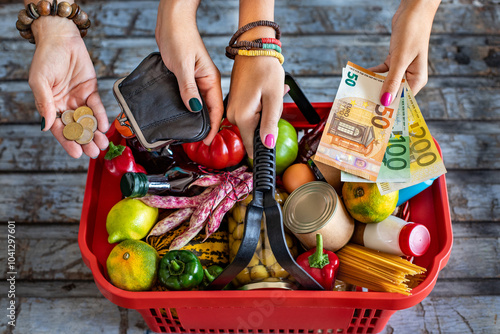 Hands of consumers when they are paying their supermarket shopping. Supermarket basket with vegetables and fruits. 