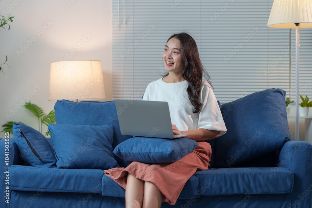 Modern working lifestyle Asian businesswoman sitting on sofa at home office working on laptop online using internet to get information, chat, to shop happily online. Modern working lifestyle Asian businesswoman sitting on sofa at home office working on laptop online using internet to get information, chat, to shop happily online.