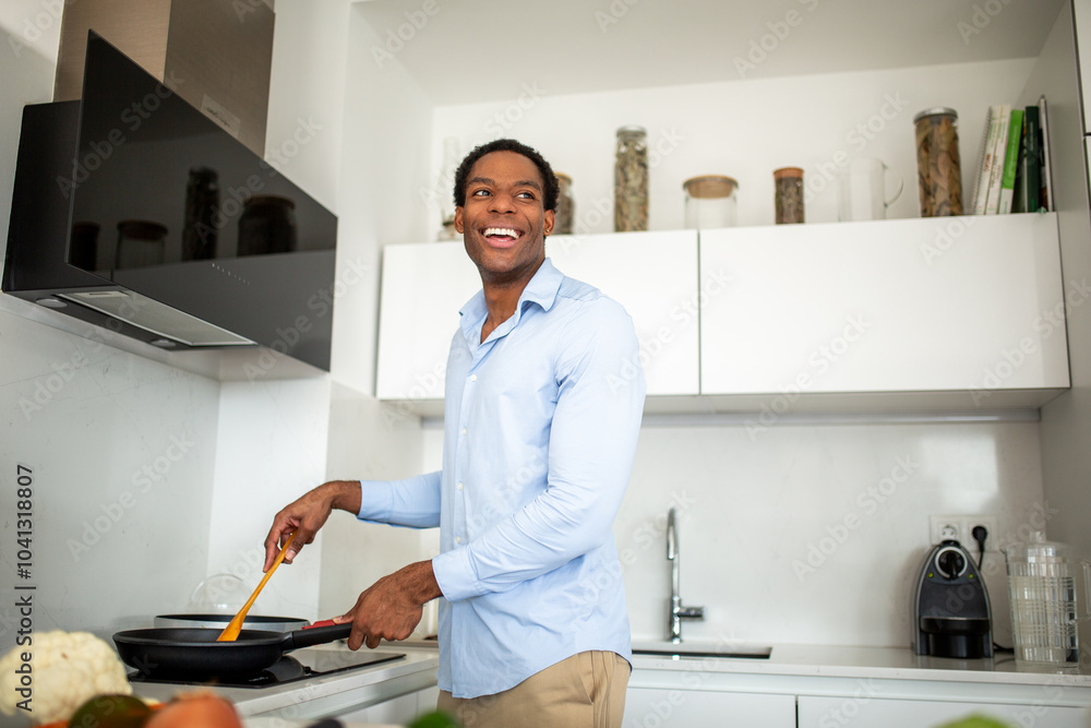Man smiling while cooking in modern kitchen with frying pan Man smiling while cooking in modern kitchen with frying pan