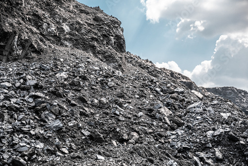 Anthracite coal deposits. Texture coal. Natural black coals for background. Industrial coal. Coal mining. Close-up of a pile of anthracite or dark rocky material under an open sky.