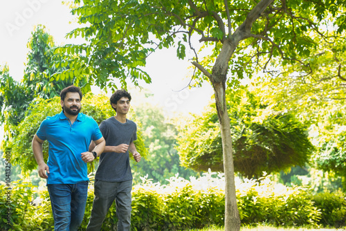 Young indian father and son running or jogging at summer park, healthy lifestyle concept. Fitness