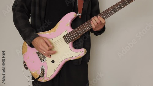 A man passionately plays a pink electric guitar in a close-up performance shot. Ideal for music, rock, concert, or creative-themed footage, with vibrant color and energetic style