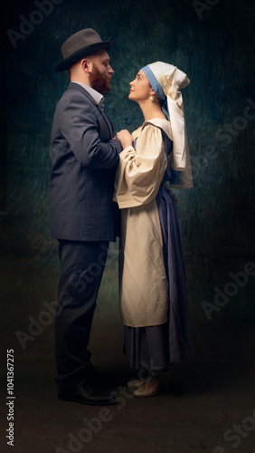 Cinematic full-length portrait of man in a suit and elegant woman in dress and headscarf standing closely to each other and holding hands. Love. Concept of art, eras comparison, creative vision, ad