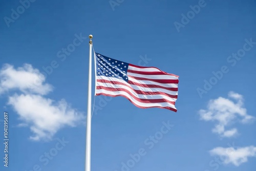 American flag waving in the wind against a blue sky with white clouds.