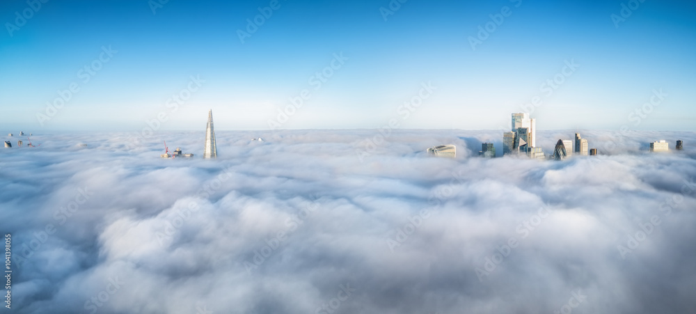 Elevated, panoramic view of the skyline of London, England, during fog with only the tips of the skyscrapers looking out above the clouds