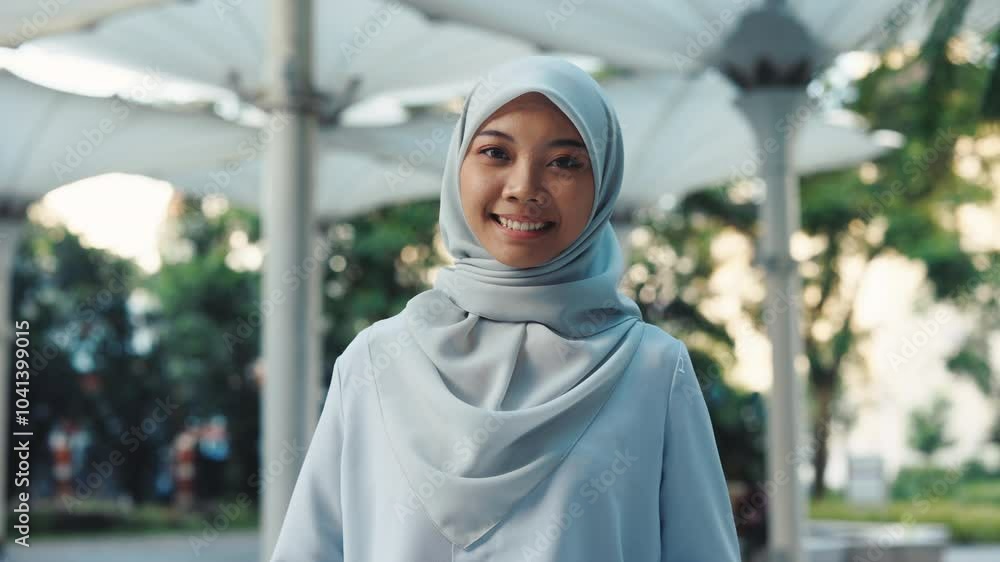Positive Charming Woman Wearing Hijab Standing Outdoors Looking at Camera on Park Background. Attractive Young Muslim Lady Posing, Looking at Camera in Centre. People and Traditions Concept Positive Charming Woman Wearing Hijab Standing Outdoors Looking at Camera on Park Background. Attractive Young Muslim Lady Posing, Looking at Camera in Centre. People and Traditions Concept