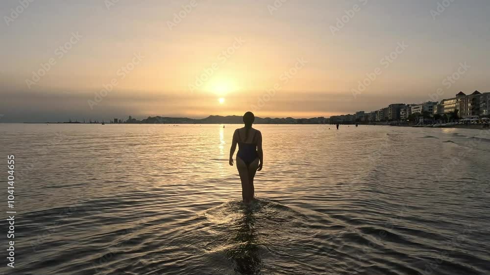 Silhouette of a woman in Durres beach walking to the sunset, skyline against a backdrop of soft clouds and tranquil waters making a dreamy landscape. Silhouette of a woman in Durres beach walking to the sunset, skyline against a backdrop of soft clouds and tranquil waters making a dreamy landscape.
