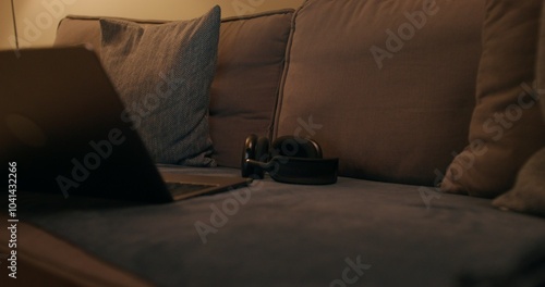 Foto An open laptop and headphones are on the couch in the apartment, the evening lig