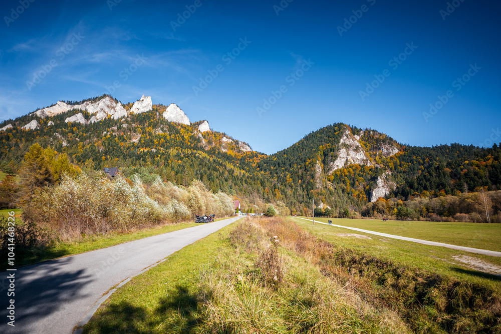 Beautiful mountains with rocky peaks in autumn on a sunny day. Pieniny Mountains. Asphalt road at the foot of the mountains View of Trzy Korony (Three Crowns). Sromowce Nizne, Poland