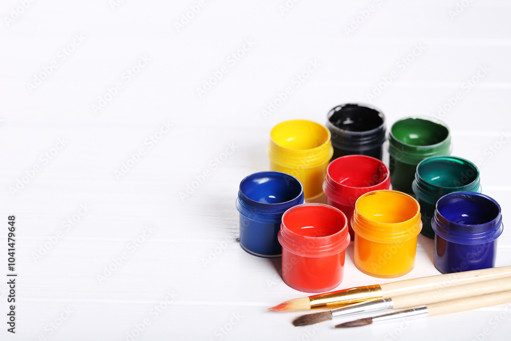 Colorful gouache paints and brushes on white wooden table Colorful gouache paints and brushes on white wooden table