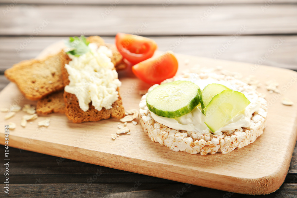 Crispbread with cream cheese and vegetables on wooden board