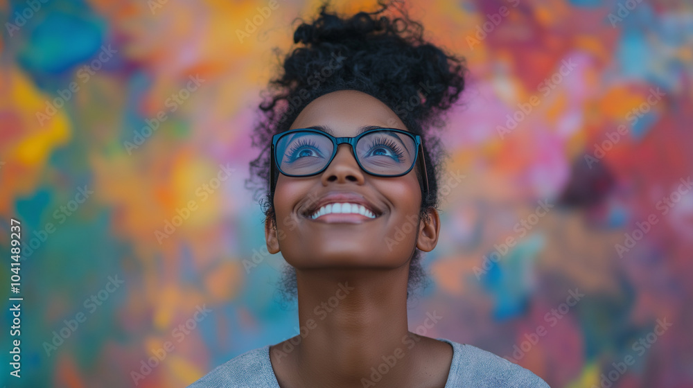 A smiling woman with glasses, looking up at colorful splashes of paint above her head, symbolizing creativity and inspiration. The background is neutral to highlight the colors in A smiling woman with glasses, looking up at colorful splashes of paint above her head, symbolizing creativity and inspiration. The background is neutral to highlight the colors in