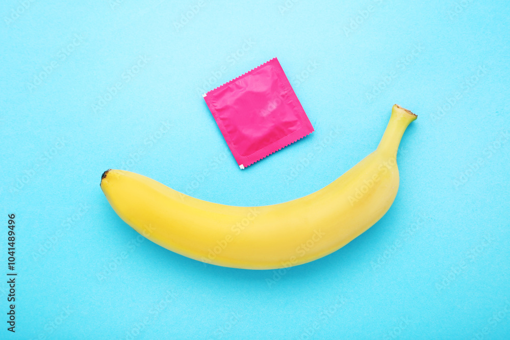 Banana with condom on blue background