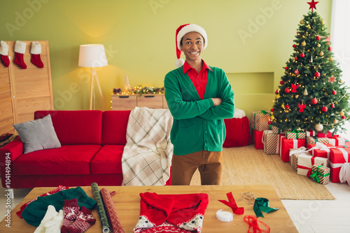 Photo of funky cool guy dressed green cardigan arms crossed wrapping x-mas gifts indoors house apartment room