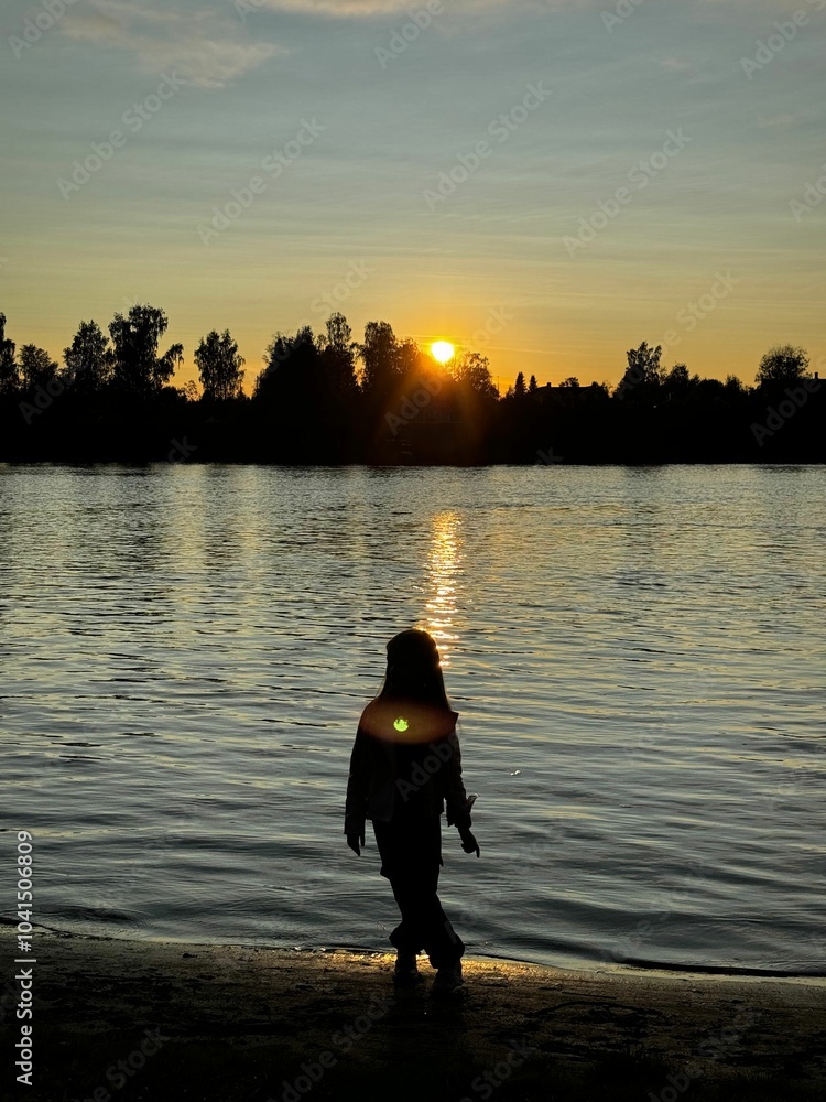 Fototapeta premium Child silhouette by lake at sunset
