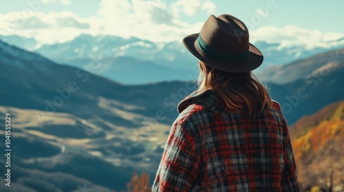 Fashionable woman in a checkered coat and hat admires a stunning mountain view under a clear sky