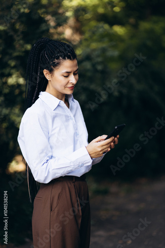 Portrait of woman with braided hair talking on the phone outside the park