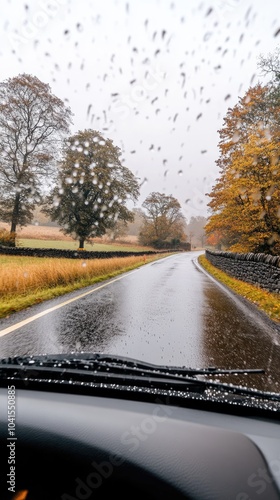 Rain falls gently along a winding road, bordered by stone walls and vibrant autumn foliage, showcasing the beauty of the English countryside photo