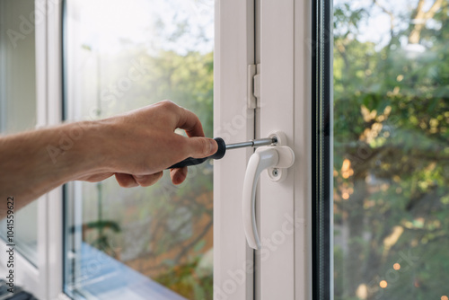 A hand repairs a window lock using a screwdriver photo