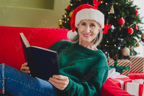 Photo of nice lovely old lady wear green clothes sit divan read book enjoy x mas holidays new year weeekend indoors home room photo