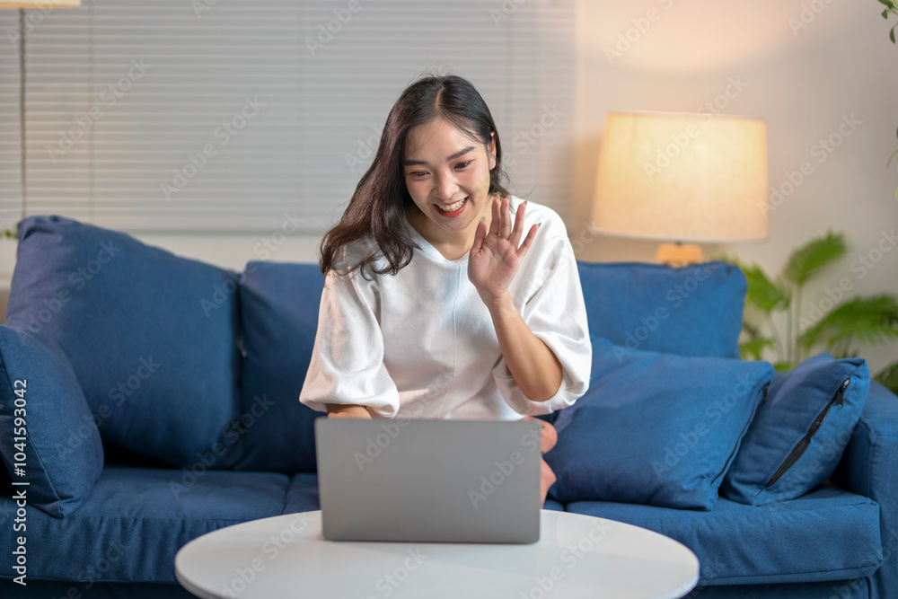Young asian woman waving during video call on laptop at home Young asian woman waving during video call on laptop at home