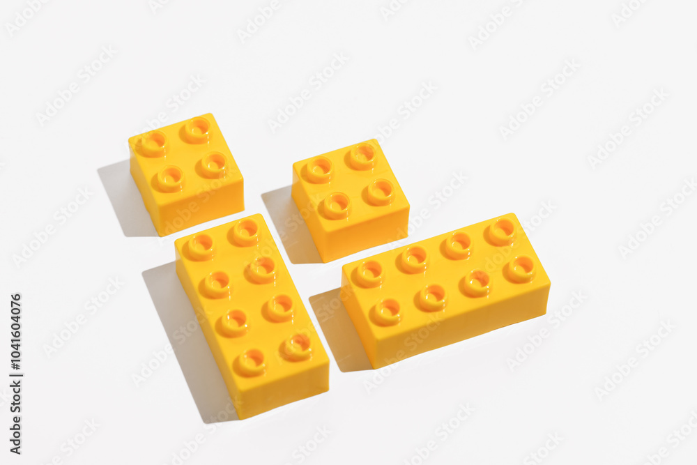 Close up of yellow plastic blocks bricks toy for building constructor on white isolated background in corner. The concept of children's educational games. Image for your design Close up of yellow plastic blocks bricks toy for building constructor on white isolated background in corner. The concept of children's educational games. Image for your design
