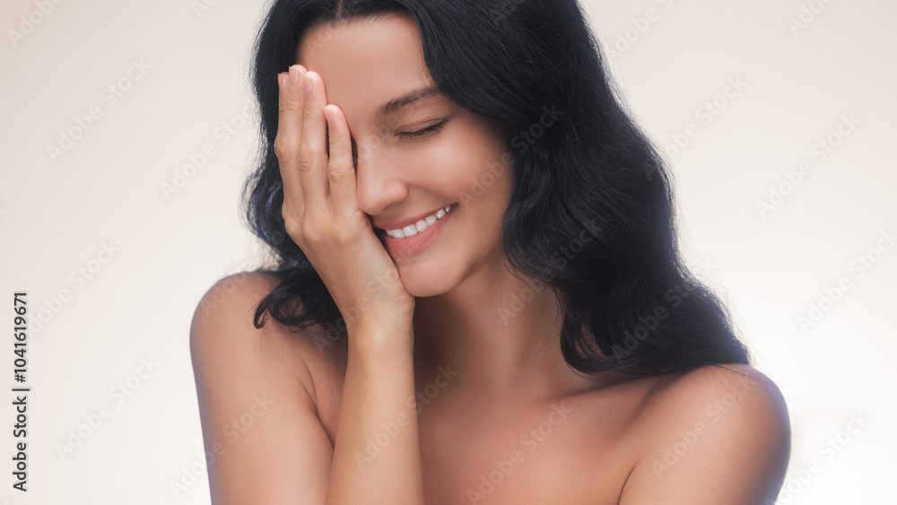A serene woman with dark hair and glowing skin smiles gently while covering one eye, exuding relaxation and natural beauty. Perfect for skincare, wellness, and beauty advertising campaigns focused on A serene woman with dark hair and glowing skin smiles gently while covering one eye, exuding relaxation and natural beauty. Perfect for skincare, wellness, and beauty advertising campaigns focused on