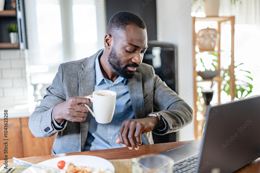 Thoughtful African-American man in business attire enjoying a cup of coffee in a modern kitchen, taking a quiet moment before work. He appears reflective and calm. Thoughtful African-American man in business attire enjoying a cup of coffee in a modern kitchen, taking a quiet moment before work. He appears reflective and calm.
