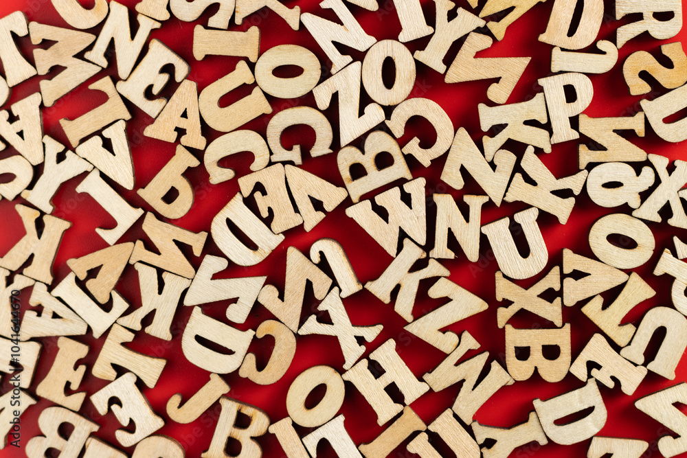 wooden letters scattered on red background. selective focus. wooden letters scattered on red background. selective focus.