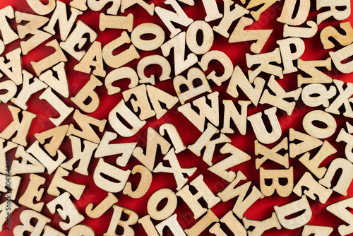 wooden letters scattered on red background. selective focus.