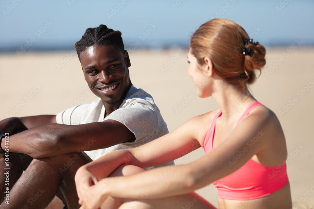 couple sited in the sand looking out into the sea couple sited in the sand looking out into the sea