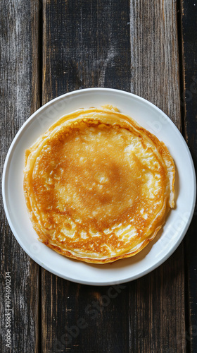 Beautifully cooked pancake on a white plate, set against a rustic wooden background, beckons you to savor a delicious breakfast indulgence