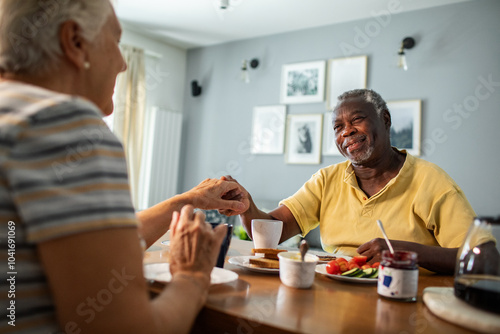 Happy senior couple eating breakfast together at kitchen table