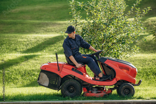 Sitting on the lawn mover. Professional gardener is on the lawn