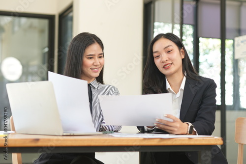 Happy Asian business people working together using laptop and tablet in office.