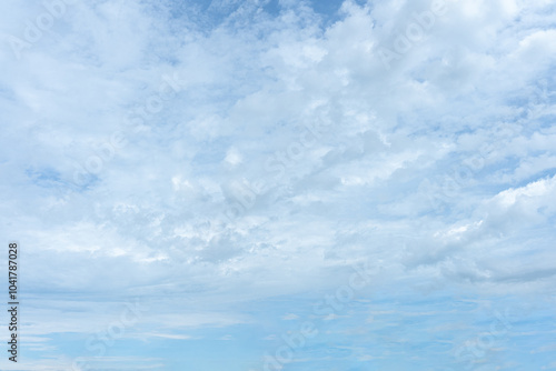 Fluffy white clouds drift across a bright blue summer sky