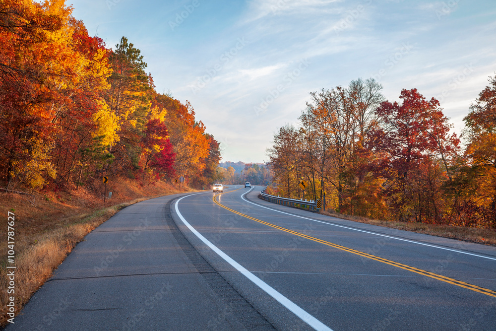 Cars travel along a curve in the road near the Mississippi River in Brainerd Minnesota on an autumn morning Cars travel along a curve in the road near the Mississippi River in Brainerd Minnesota on an autumn morning