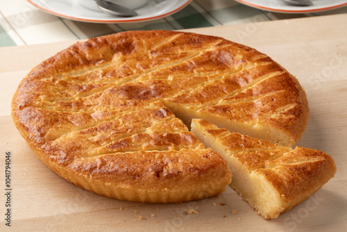 Single traditional fresh baked Dutch Boterkoek, butter cake and a piece on a cutting board close up photo