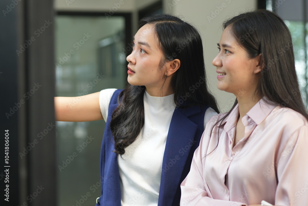Two professional business executives working on laptop computer sitting at office desk, happy colleagues discussing company digital strategy.