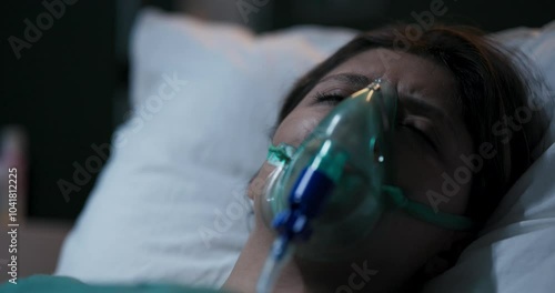Young patient waking up suddenly in hospital bed with oxygen mask.