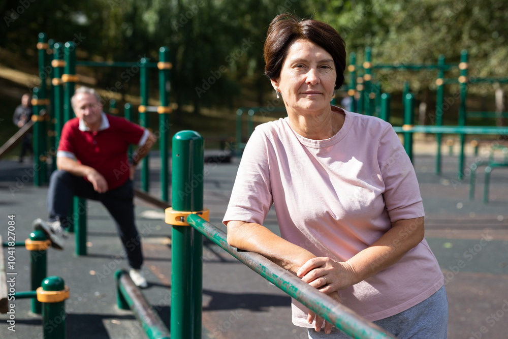 Fototapeta premium Elderly woman stands in a sports bar on an outdoor sports field