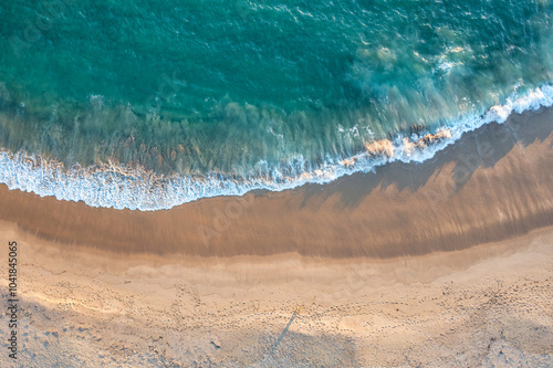 Beach sand sea water summer background. Sand beach desert texture. White foam wave sandy seashore top view.