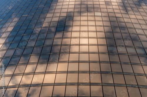 Windows of building at sunset. Reflection of the sky in the window glass. Skyscrapers in business district against blue sky. Looking up high-rise office buildings. Angled view.