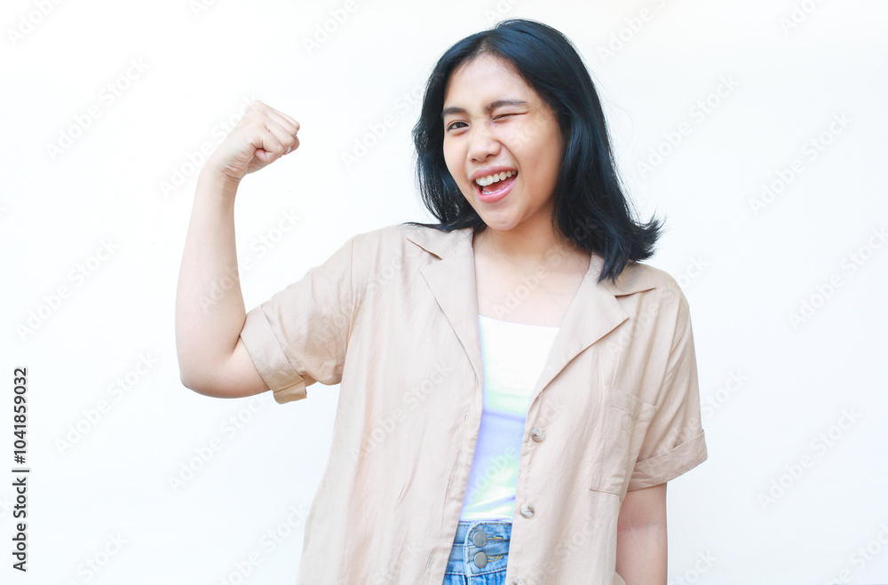 happy asian woman celebrate victory with raised fist wearing casual brown clothes isolated on white background happy asian woman celebrate victory with raised fist wearing casual brown clothes isolated on white background