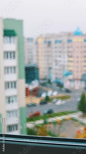 Brush washing window upstairs of a tall city building. Cleaning plastic window from outside on the urban background. View from indoors. Vertical video photo