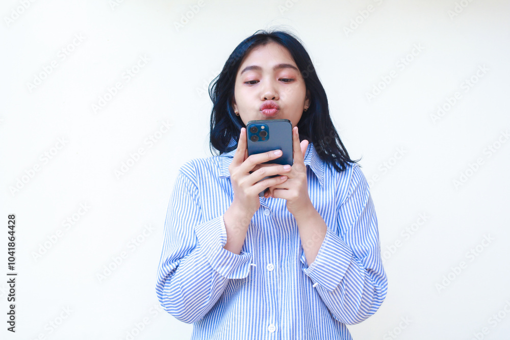 thoughtful asian woman using smartphone thinking problem wearing blue striped casual shirt standing over isolated white background thoughtful asian woman using smartphone thinking problem wearing blue striped casual shirt standing over isolated white background