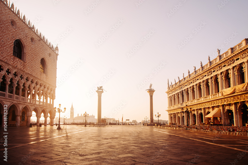 Fototapeta premium Breathtaking Sunrise at San Marco Square in Venice, casting warm light on the historical architecture and quiet cobblestone pathways, creating a serene atmosphere for early morning wanderers. Italy
