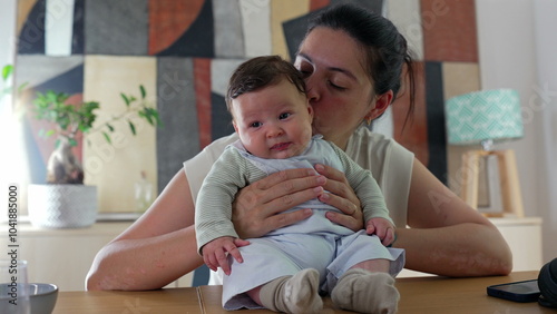 Mother smiling warmly at her baby while holding the child on a table in a cozy indoor setting. peaceful family bonding moment between a mother and her happy baby