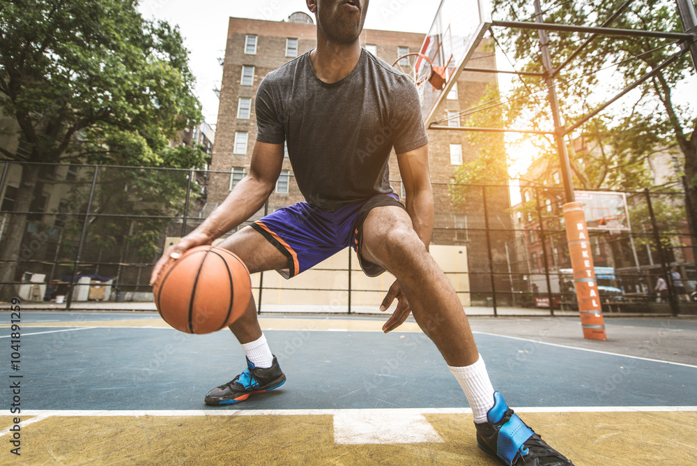 Black sportive basketball player playing basketball on a court in New York City Black sportive basketball player playing basketball on a court in New York City