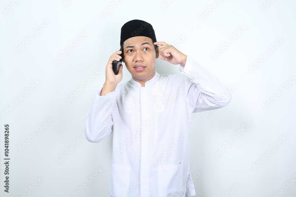 asian muslim man touching his head show confused expression while talking on the phone isolated on white background asian muslim man touching his head show confused expression while talking on the phone isolated on white background
